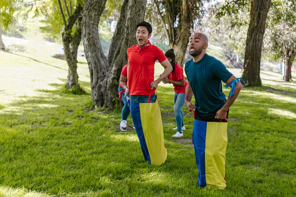 Group of adults enjoying a fun sack race in a vibrant park setting.