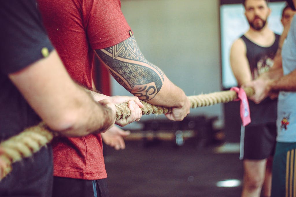 Group of adults participating in a thrilling tug of war game indoors with focus on teamwork and competition.